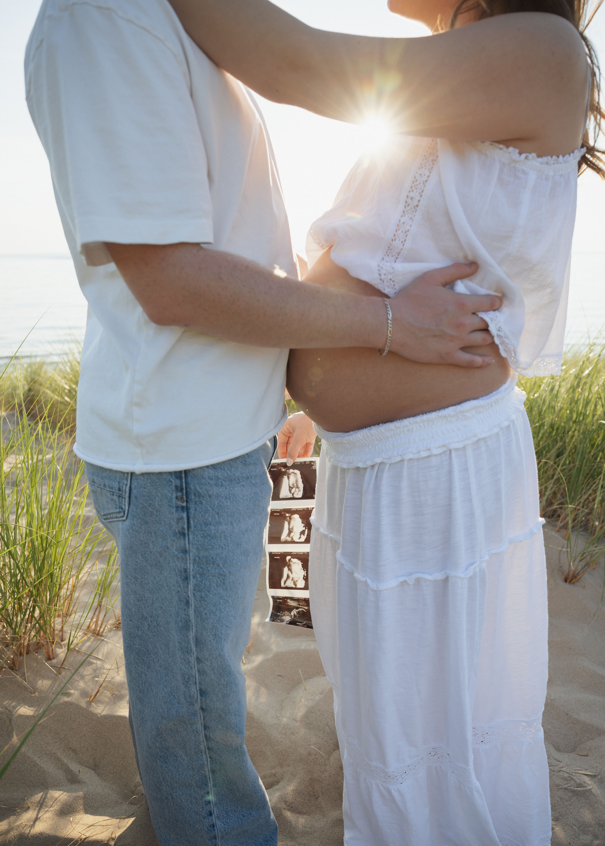 Expecting mother and partner on the beach at golden hour
