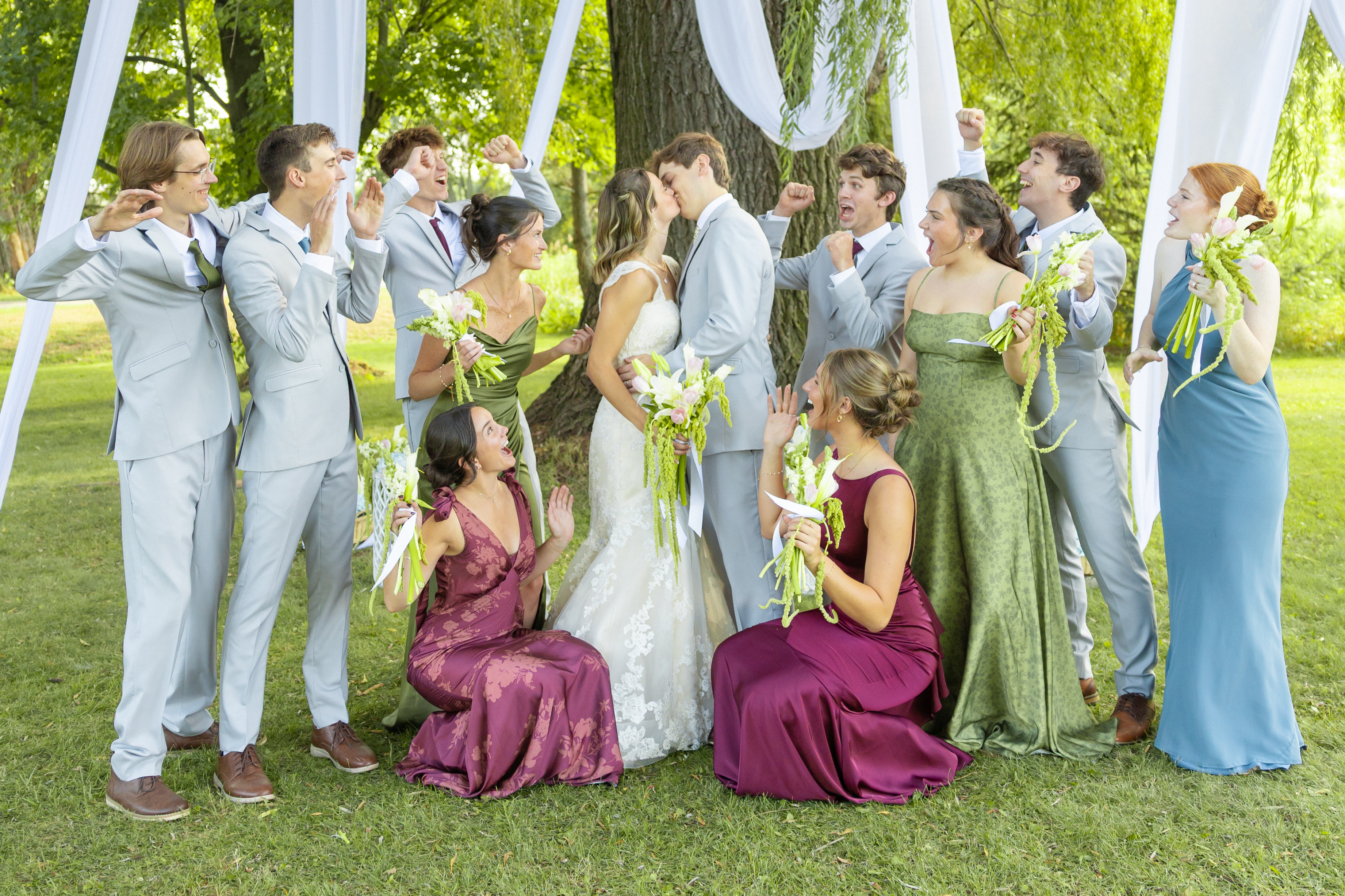 Bride and groom celebrating with their wedding party under an oak tree